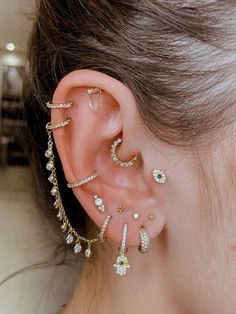 a woman's ear is adorned with gold and crystal jewelry, including an ear cuff