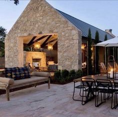 an outdoor dining area with patio furniture and stone building in the background at night time