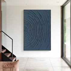 an abstract painting hangs on the wall next to a stair case in a modern home