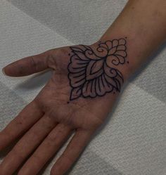 a person's hand with a black and white tattoo design on the left palm