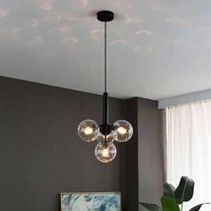 a modern chandelier hanging from the ceiling in a living room with grey walls