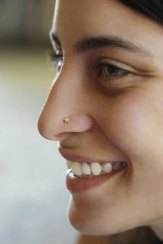 a close up of a woman with a nose piercing on her left side smiling at the camera