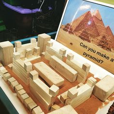 a wooden model of the great pyramids in front of a sign that says can you make a pyramid?