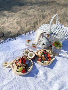 two plates with food on them sitting on a white towel next to a basket filled with strawberries