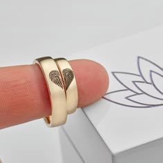 a person's finger is shown with two rings in front of a white box