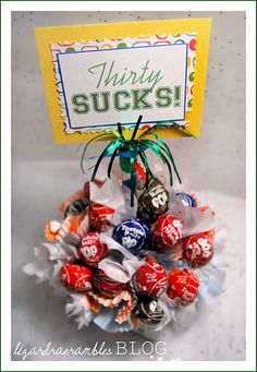 a bunch of candy in a vase with a sign on it that says thirty sucks