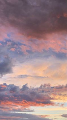 an airplane is flying in the sky at sunset or dawn with clouds and blue, pink, orange and yellow colors