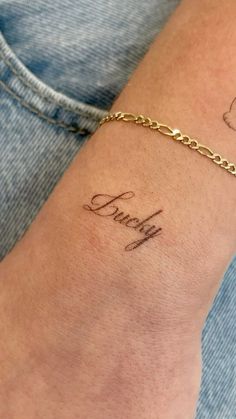 a woman's arm with a name tattoo on it and a chain around the wrist