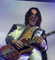 a man with long hair playing an electric guitar