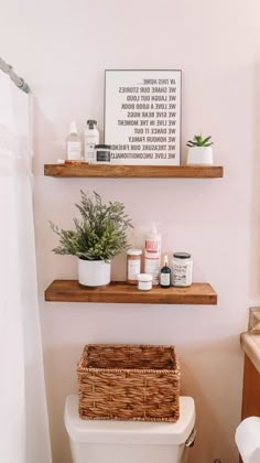 a bathroom with two shelves above the toilet and a basket on the back of the toilet