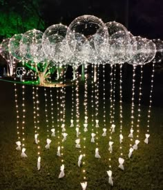 an outdoor display with lights and balloons in the shape of birds hanging from it's branches