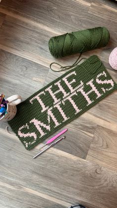 there is a green knitted mat with the words she walks on it next to yarn and crochet needles