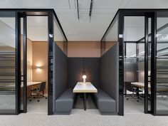 an office cubicle with two desks and chairs in the center, surrounded by glass partitions