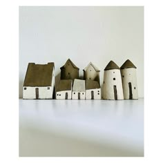 small wooden houses lined up on a white surface with one house in the middle and two buildings behind it