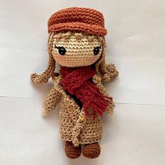 a crocheted doll with a red scarf and hat on it's head