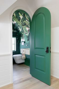 an open door leading to a bathroom with green walls and doors painted in different colors