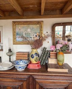 there are many books and vases on the dresser in this room, including one that is decorated with flowers