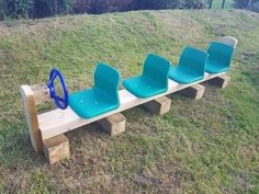 three blue chairs sitting on top of a wooden bench in the middle of a field