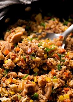 rice and vegetables are mixed together in a skillet with a spoon on the side