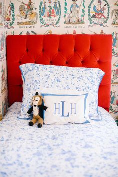 a teddy bear sitting on top of a bed in a room with wallpapers