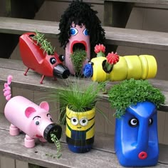 four different colored vases with plants and animals in them sitting on a wooden bench