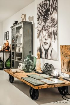 a room filled with lots of furniture and art on the wall above it is a table that has glass vases sitting on wheels in front of it