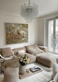 a living room filled with furniture and a chandelier hanging from the ceiling next to a window