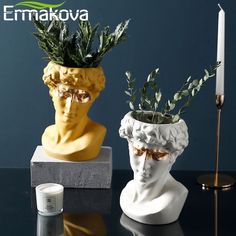 two vases with plants in them sitting on a table next to a candle holder