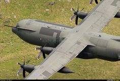 an air plane flying in the sky over some grass and rocks with two propellers on each wing