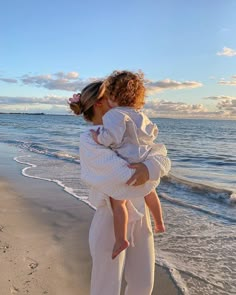 a woman holding a child on the beach