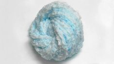 a blue ball of yarn sitting on top of a white surface