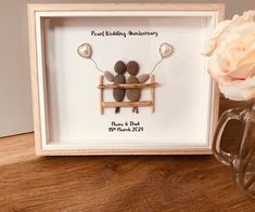 a couple is sitting on a bench with flowers in front of them and a framed photo