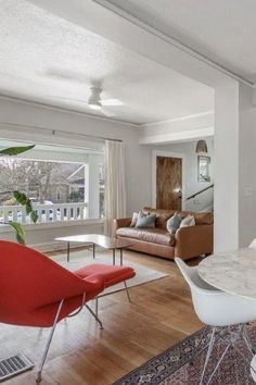 a living room filled with furniture and a white table topped with a red chair next to a window