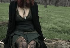 a woman with red hair sitting on a log in the grass wearing tights and stockings