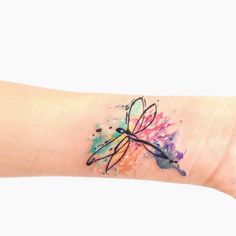 a watercolor dragonfly tattoo on the wrist