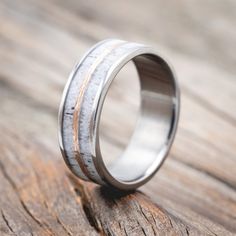 a wedding ring with antler wood inlays on the outside and inside, sitting on a wooden surface