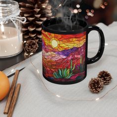 a coffee mug sitting on top of a table next to some pine cones and candles