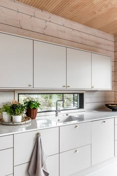 a kitchen with white cabinets and wooden ceiling