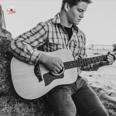 a man sitting on a rock playing an acoustic guitar