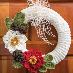 a crocheted wreath with flowers on the front door