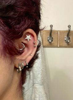 a woman wearing ear piercings with stars and moon designs on her ears, in front of a towel