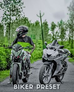 two motorcycles parked on the side of a road near some bushes and trees, one is wearing a helmet