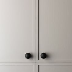 two black knobs are on the white cabinet doors