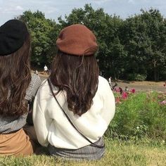 two women sitting in the grass with their backs to each other