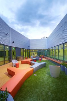 an outdoor seating area with grass and potted plants on the ground in front of two large windows