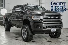 a black ram truck is parked in a large room with tile flooring and white walls