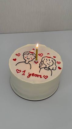 a birthday cake with two people on it and a candle in the shape of a heart