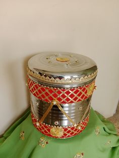 a metal container sitting on top of a green cloth covered floor next to a white wall