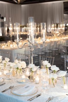 the table is set with white flowers and candles for an elegant wedding reception or special event