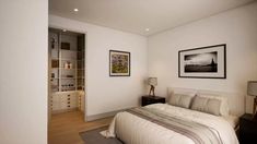 a bedroom with white walls and wood flooring has a large bed in the corner